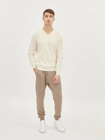 Man wearing a cream sweater and beige pants on a white background