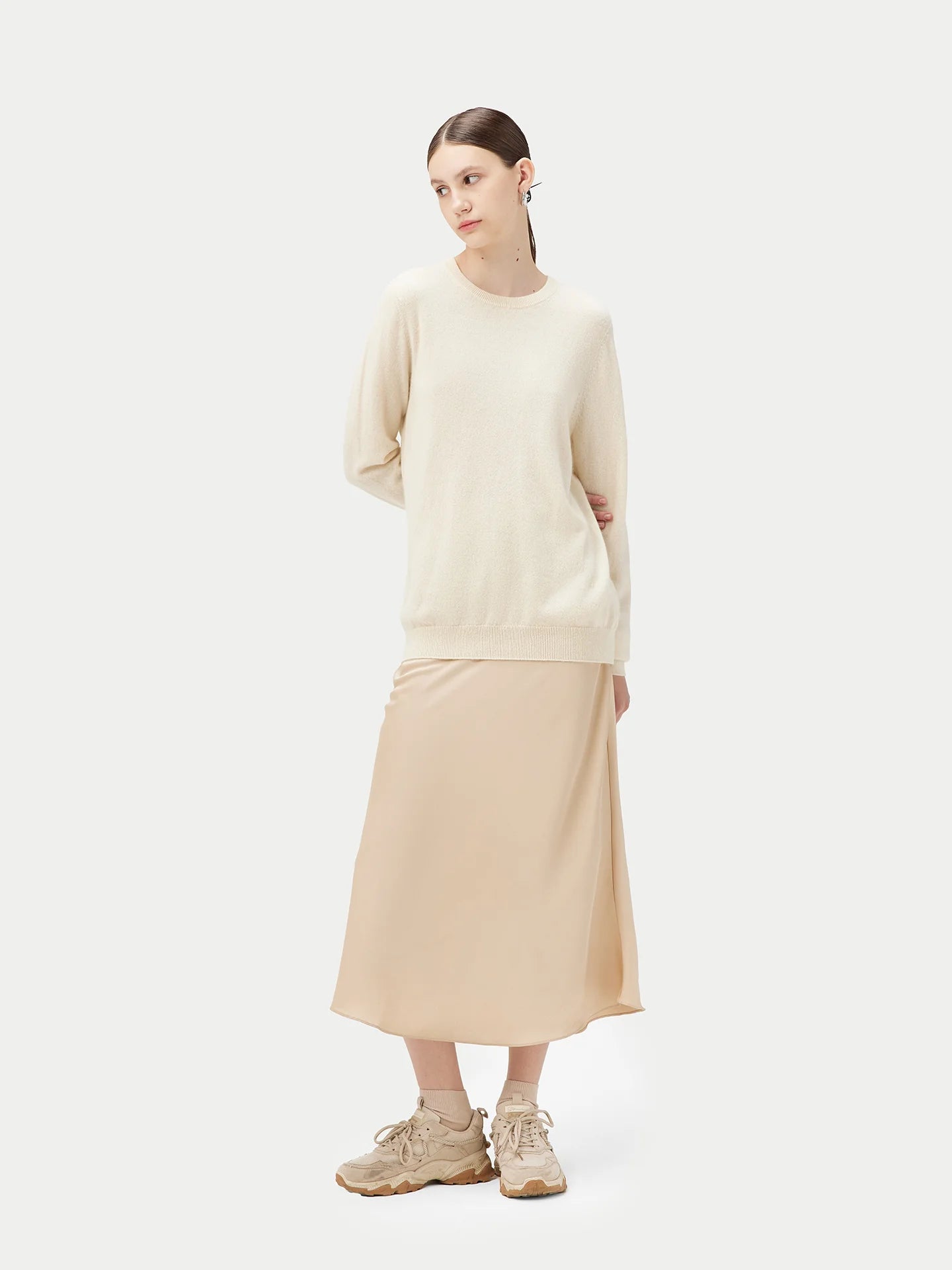 Woman wearing a beige sweater and skirt set on a white background